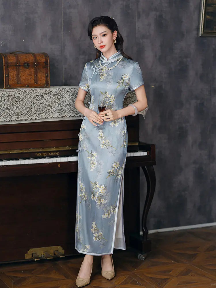 Woman in a Light Blue Mulberry Silk Floral Qipao Dress  standing in front of a piano with a dark wall background