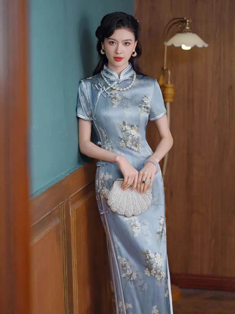 Woman in a Light Blue Mulberry Silk Floral Qipao Dress holding a handbag in a room with wooden paneling.