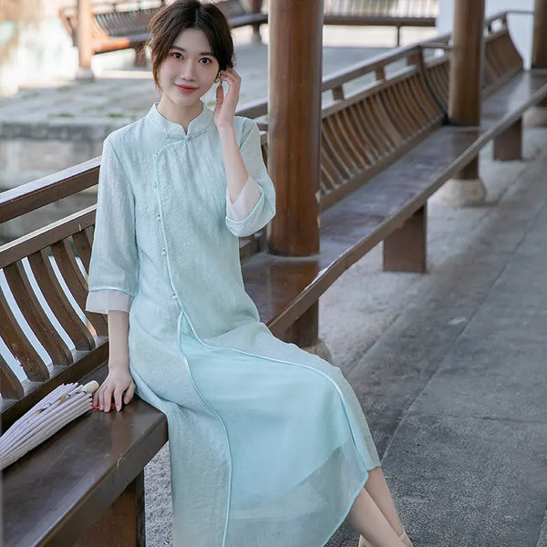 Woman in a  traditional Light Green Loose A Line Cheongsam Qipao Dress sitting on a wooden bench.