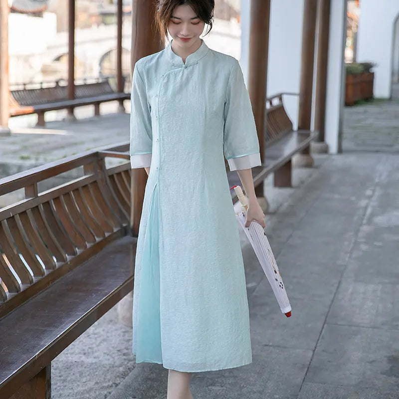 Woman in a Light Green Loose A Line Cheongsam Qipao Dress holding an umbrella on a wooden deck.