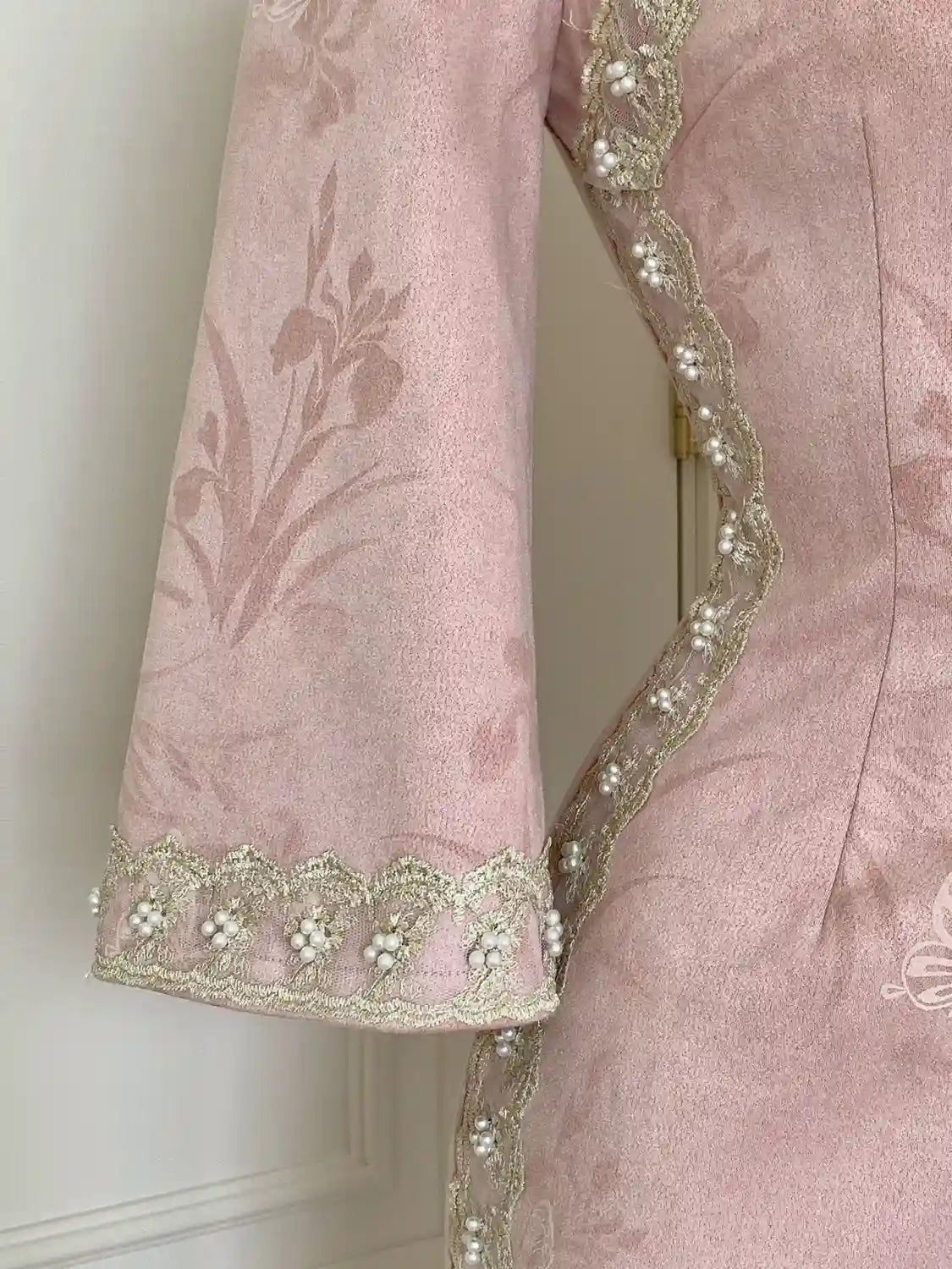 Pink embroidered garment with intricate detailing on a white background