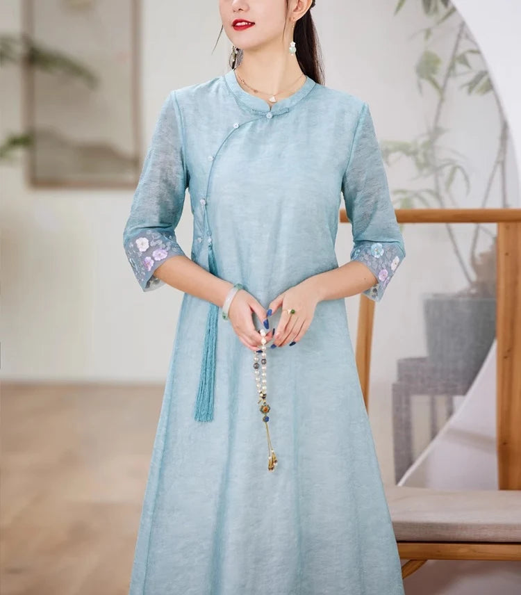 A chinese Woman wearing a light blue Loose A line Cheongsam Qipao Dress with floral cuffs in an indoor setting