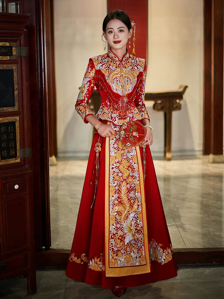 Woman wearing a traditional red and gold Luxury Embroidered Dragon & Phoenix Bridal Wedding Qun Kwa Set  with floral patterns in an indoor setting.
