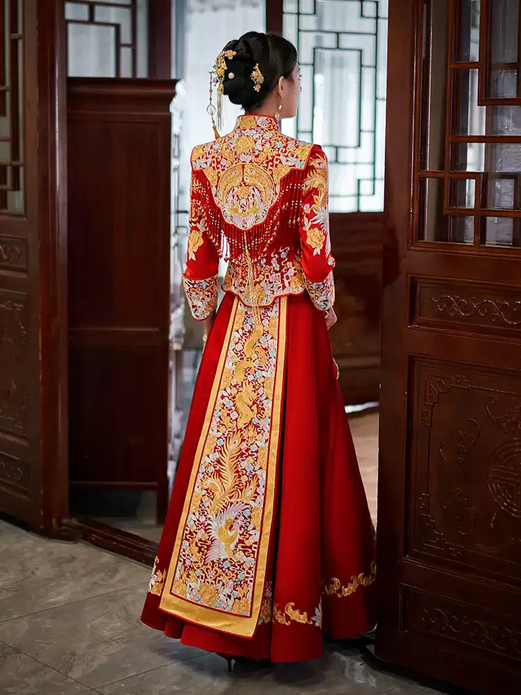 Traditional red and gold Luxury Embroidered Dragon & Phoenix Bridal Wedding Qun Kwa  dress worn by a person in a wooden interior setting