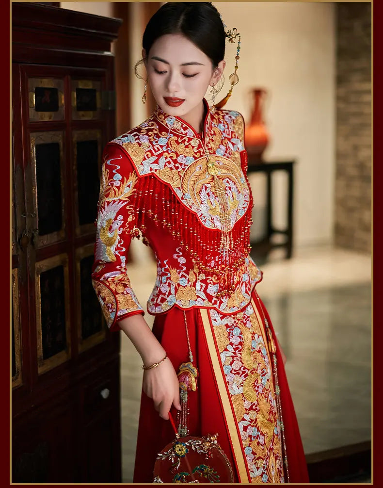 Woman wearing a traditional red and gold Luxury Embroidered Dragon & Phoenix Bridal Wedding Qun Kwa Set  in an indoor setting.