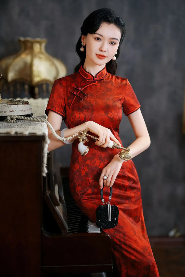 Woman in aLuxury Red Silk Qipao Dress with Maple Leaves Print holding a vintage telephone in an indoor setting