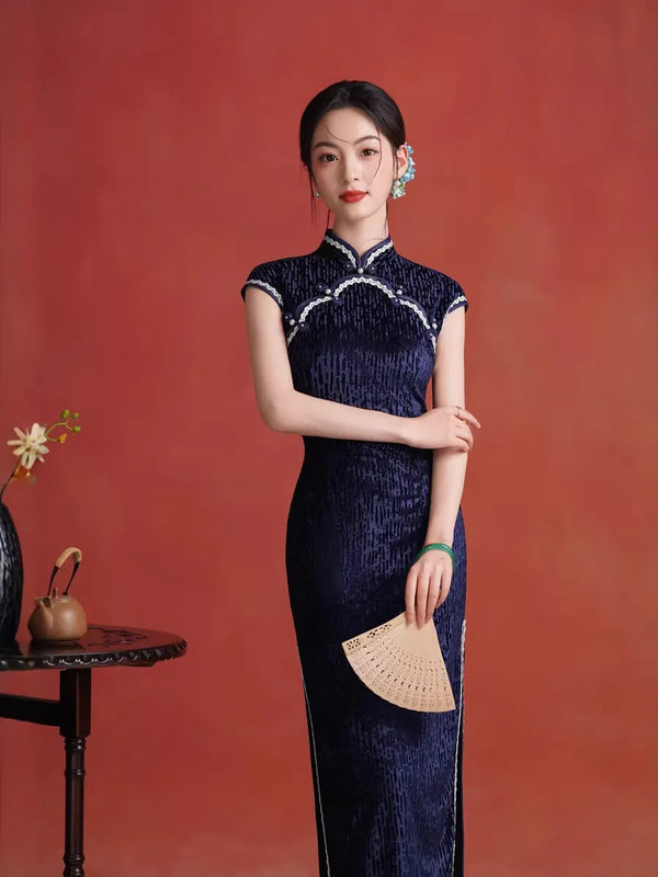 Woman in aMidnight Navy Blue Sleeveless Velvet Long traditional Chinese  Qipao  dress holding a fan against a red background