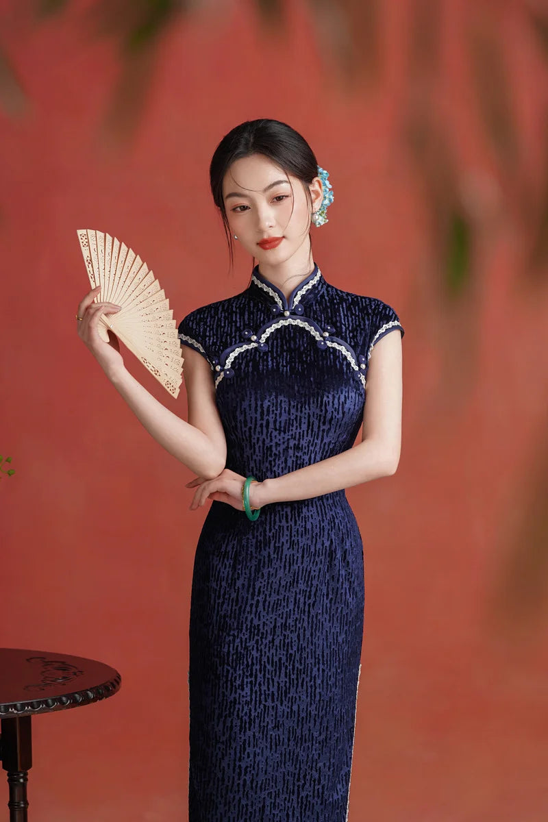 Woman in a Midnight Navy Blue Sleeveless Velvet Long  Qipao cheongsam  dress holding a fan against a red background