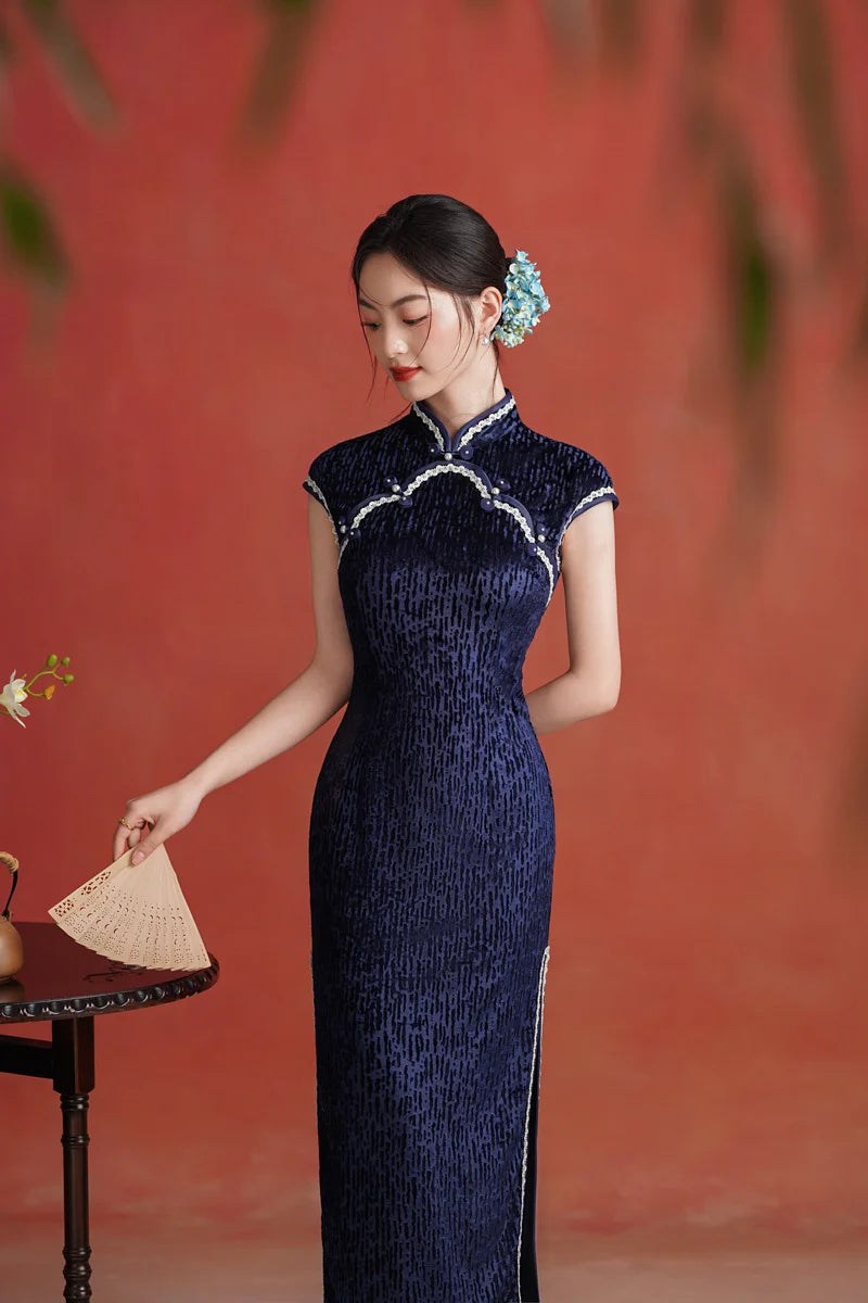 Woman in a Midnight Navy Blue Sleeveless Velvet Long  Qipao  traditional chinese dress with white trim against a red background