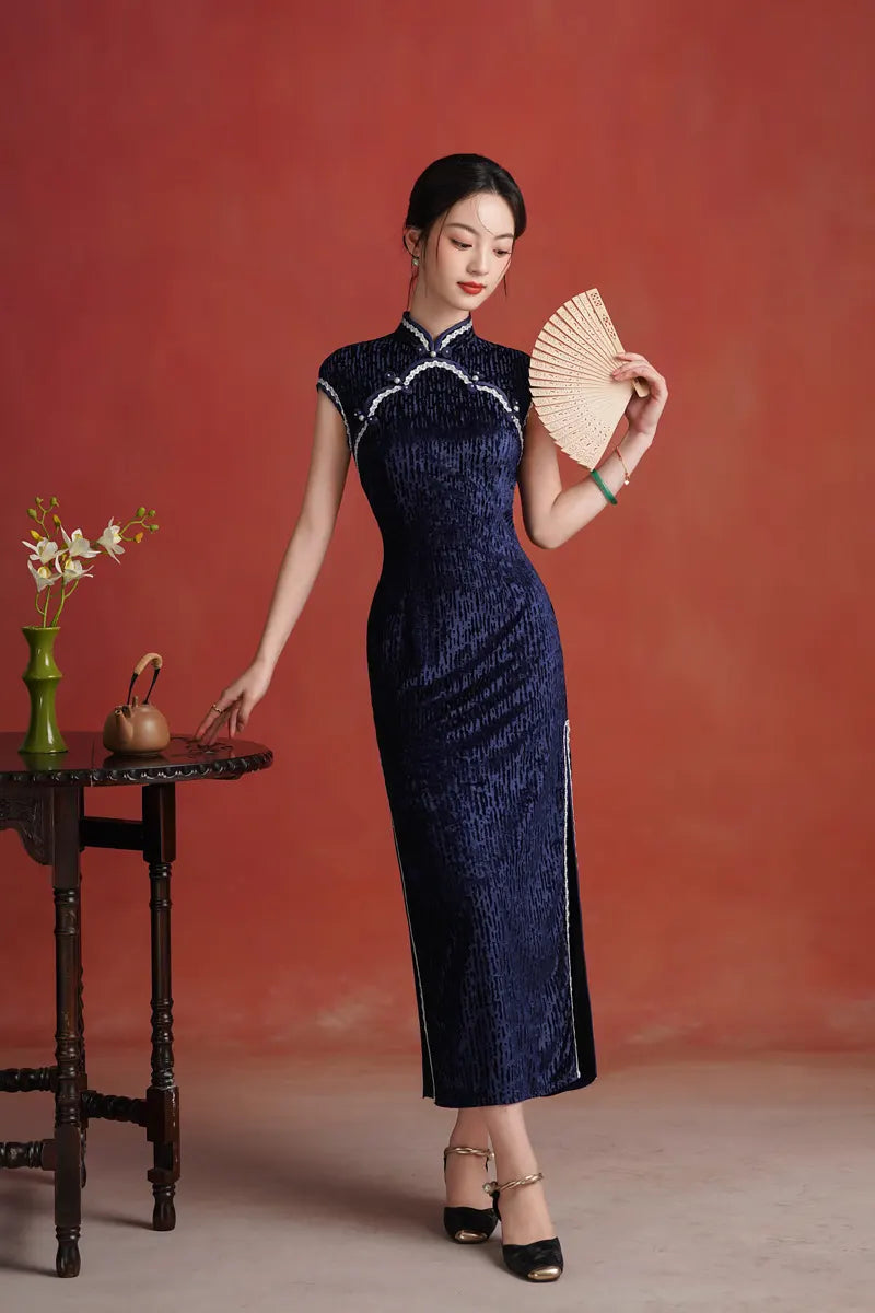 Woman in a Midnight Navy Blue Sleeveless Velvet Long  Qipaotraditional dress holding a fan against a red background