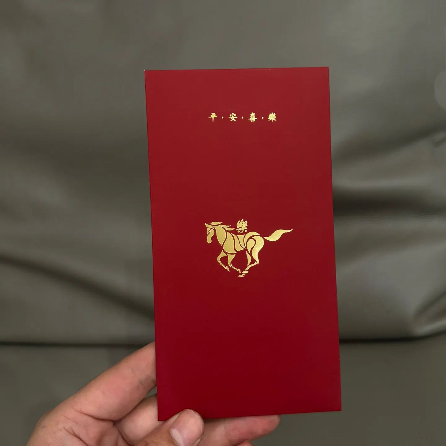 Minimalist 2026 Year of the Horse Red Envelopes - Lucky Money Packets  with gold horse design and Chinese characters held by a hand against a gray background