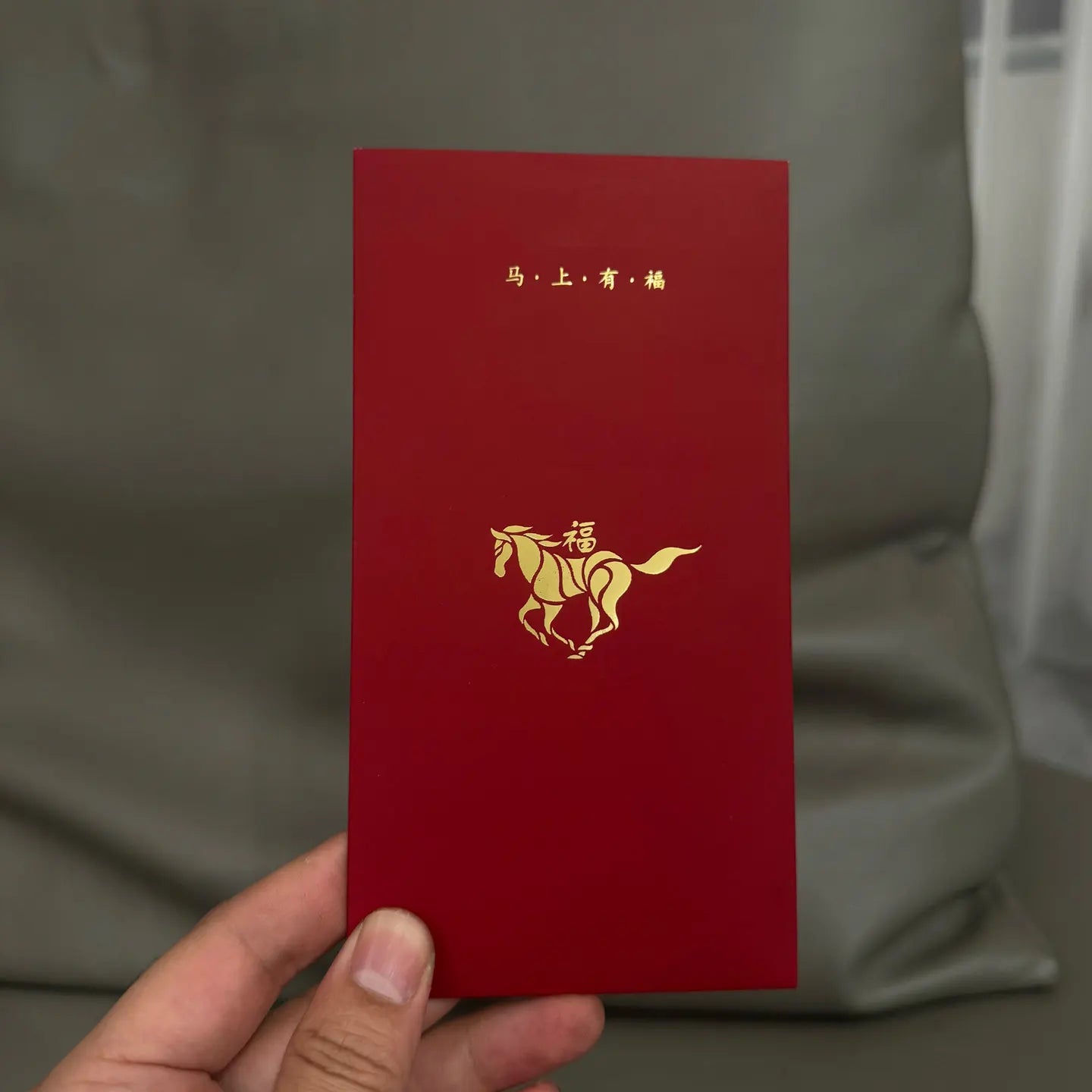 Minimalist 2026 Year of the Horse Red Envelopes - Lucky Money Packets  with gold horse design and Chinese characters held by a hand against a neutral background