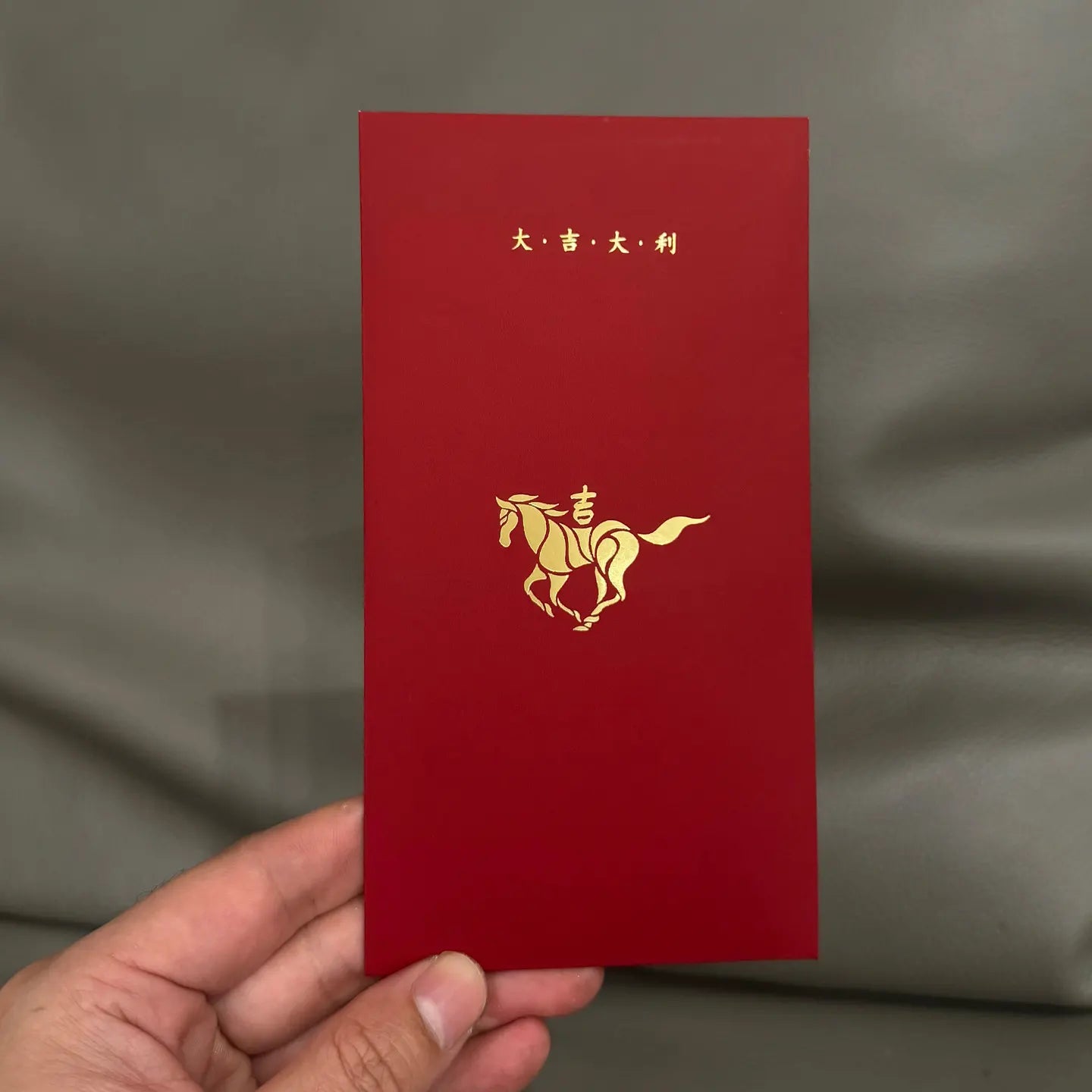 Minimalist 2026 Year of the Horse Red Envelopes - Lucky Money Packets with gold horse design and Chinese characters held by a hand against a gray background
