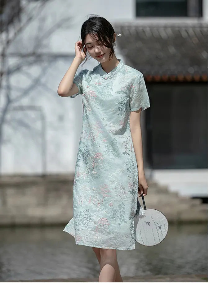 Woman wearing a light Mint Green Scenic Brocade Loose A Line Qipao cheongsam  Dress holding a round fan outdoors.