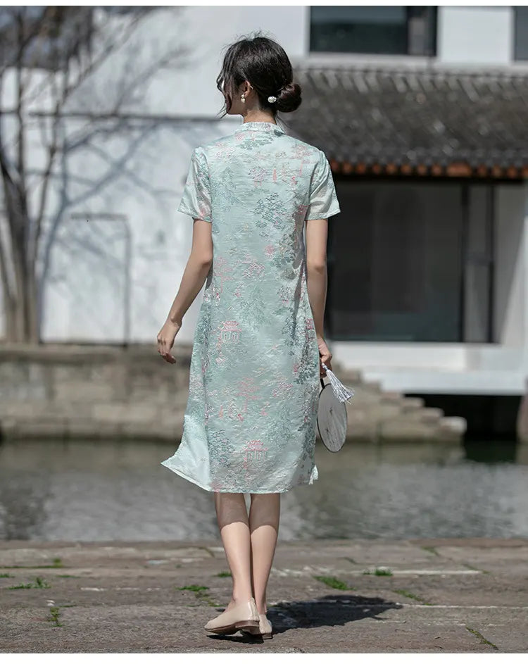 Woman in a light green floral a line loose cheongsam dress walking outdoors near a body of water.