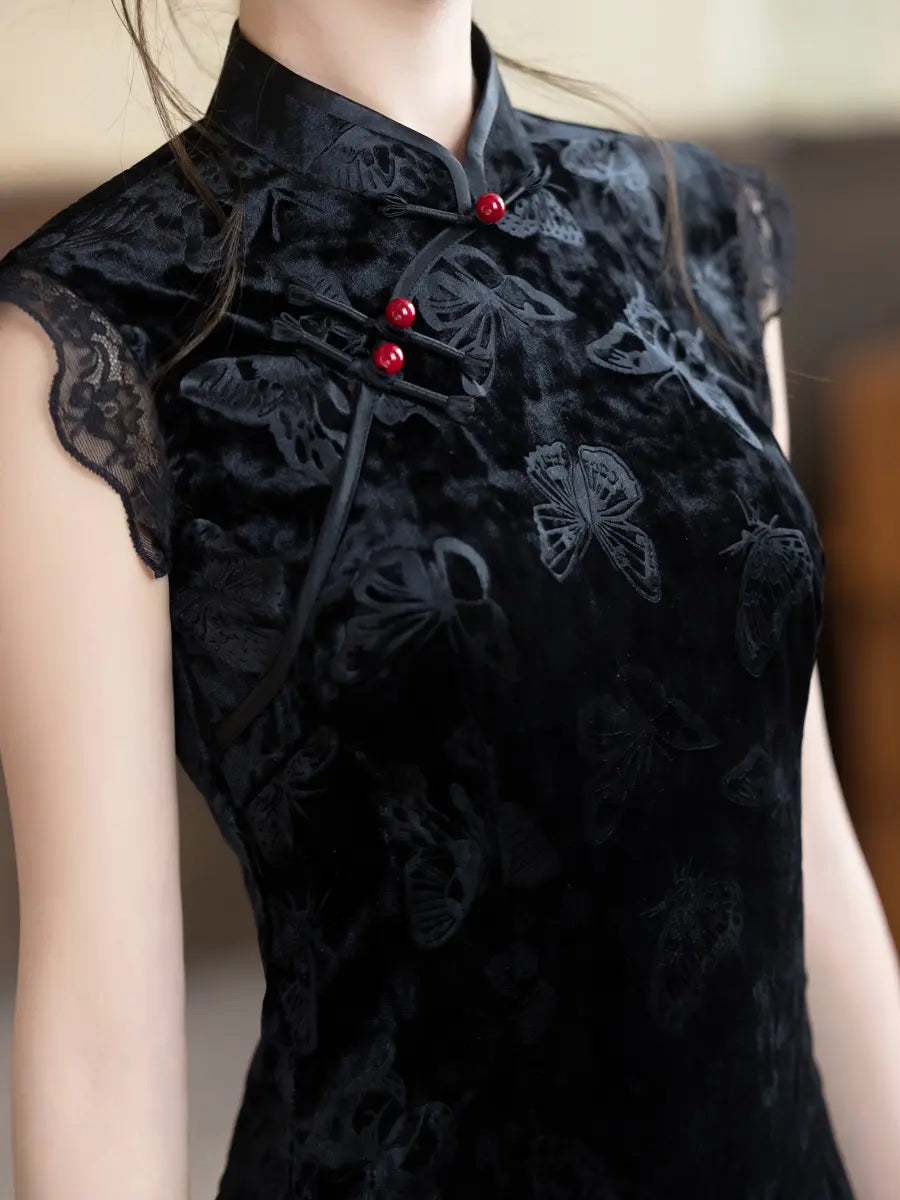 A close-up of a woman wearing a black velvet cheongsam-style top with tonal butterfly embroidery, lace trim, and red decorative buttons at the collar.