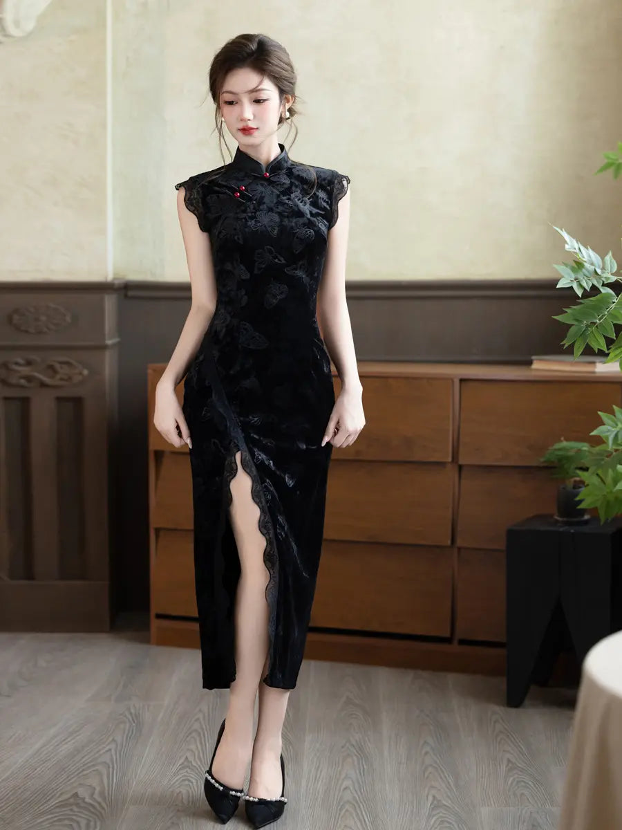 A woman models a black sleeveless floral lace cheongsam dress with a high thigh slit, standing in a room with wooden furniture and plants.