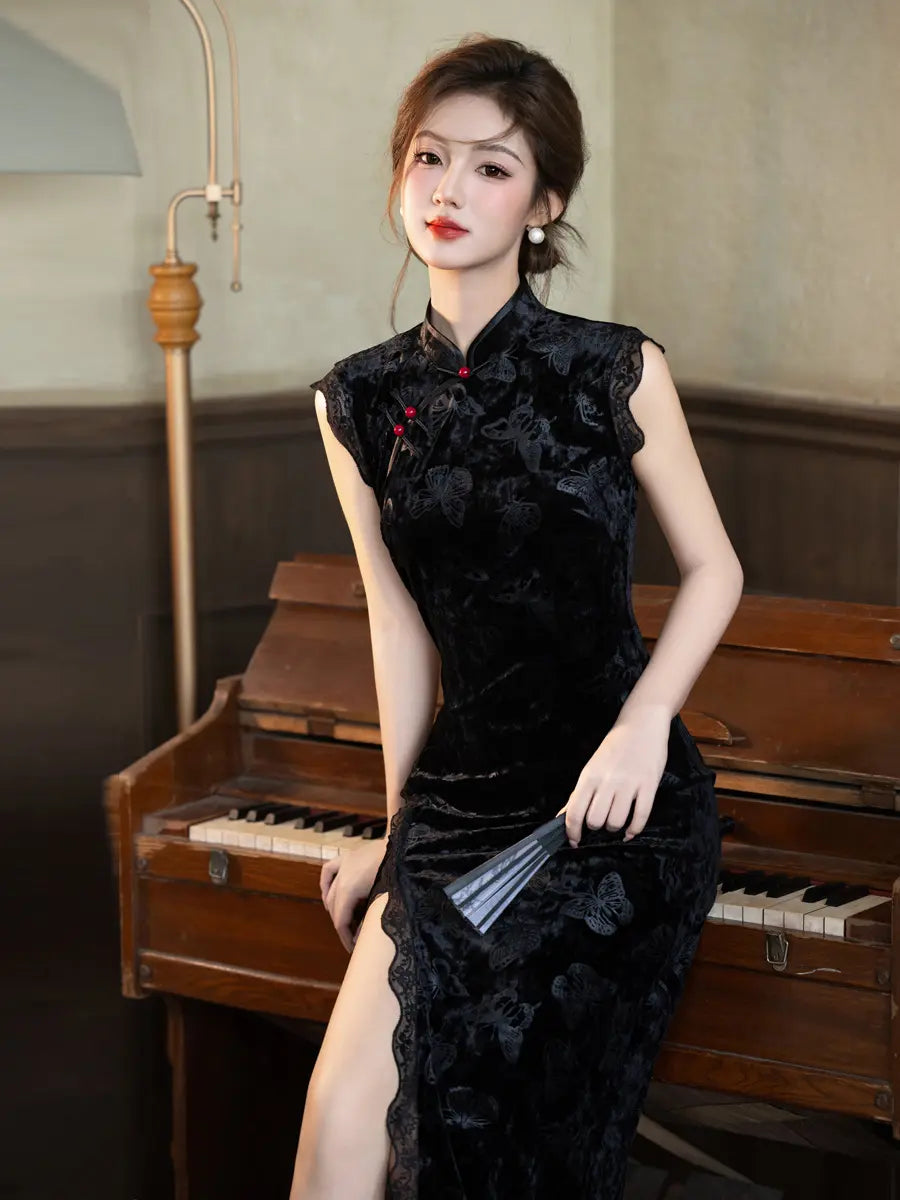 A woman wearing a black floral velvet modern qipao cheongsam dress with red buttons, posing in front of a vintage wooden piano.
