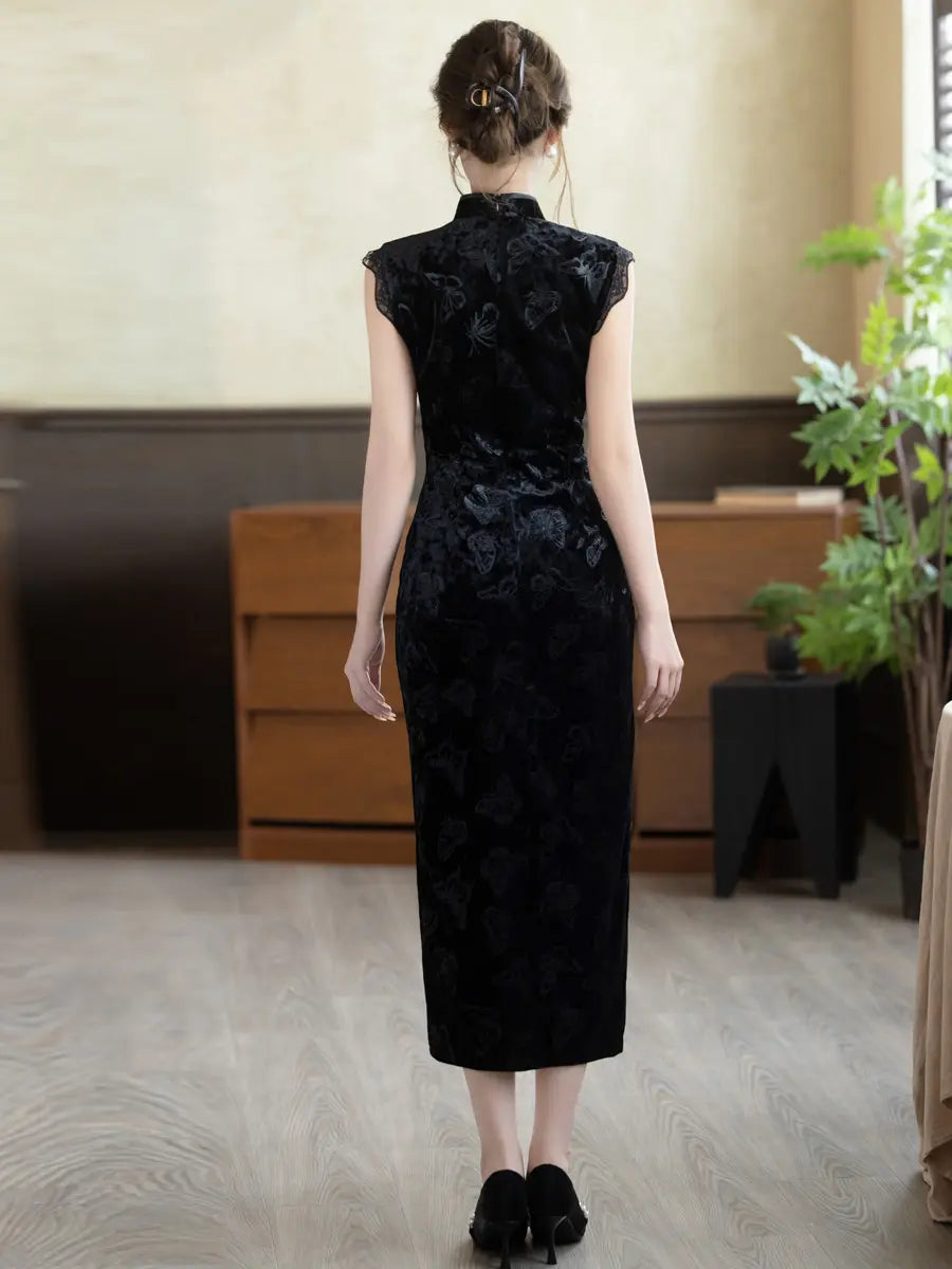 A woman viewed from behind wearing a sleeveless black cheongsam-style dress with a floral jacquard pattern, standing in an indoor room with wood flooring and furniture.