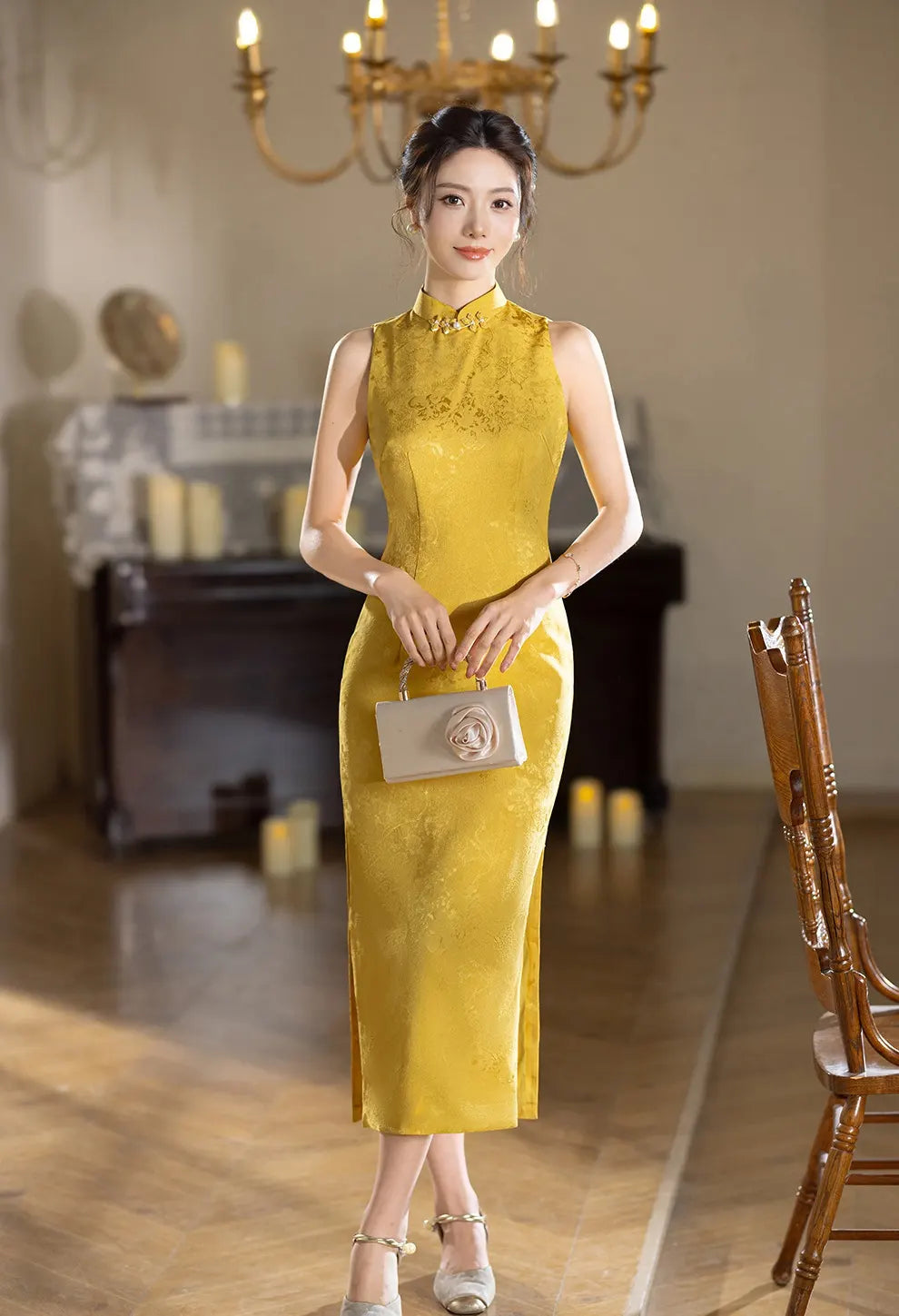 Woman in a Modern Imperial Gold Open Back Jacquard Qipao Dress  standing in an elegant room with a chandelier.