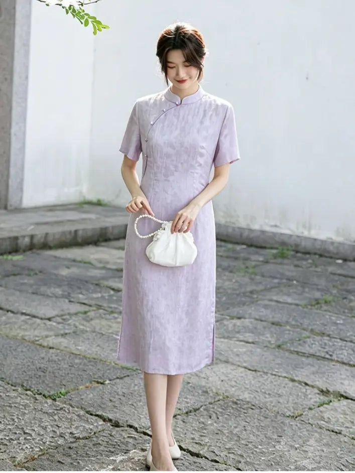 Woman in a light purple Modern Lavender A-line Short Sleeve Summer Qipao Dress  holding a white handbag on a stone path.