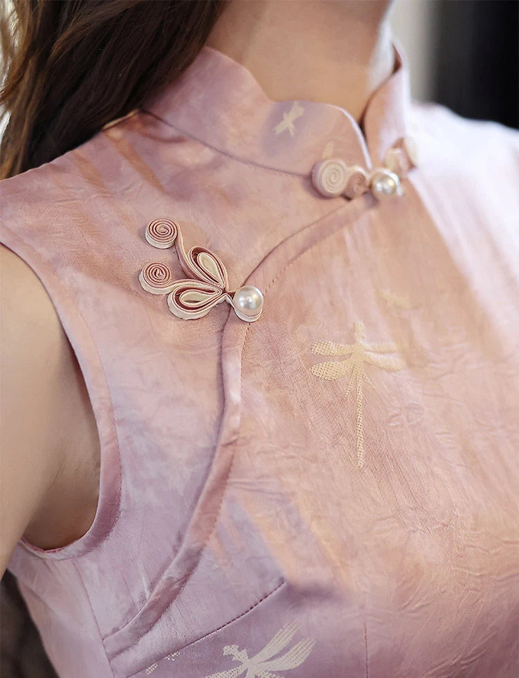 Close-up of a light pink traditional Modern Minimalist  Sleeveless Qipao With Dragonfly Print outfit with decorative buttons and embroidery.