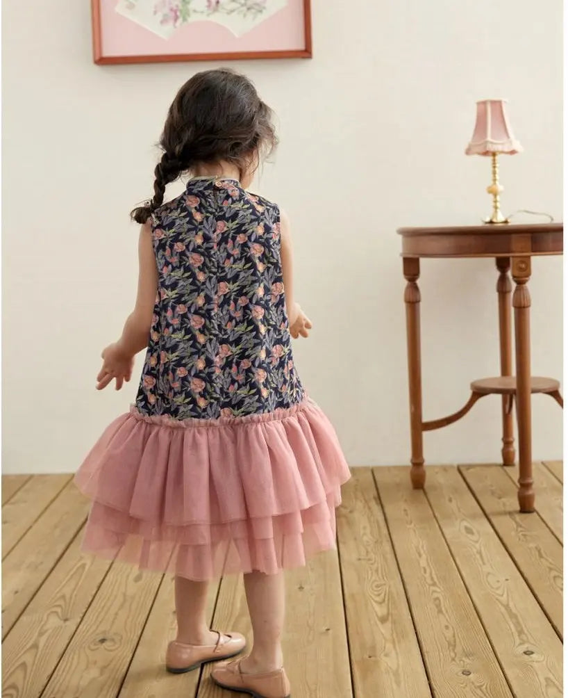 Child wearing a Modern Pink Floral Tulle Qipao Dress standing in a room with wooden flooring and a small table.