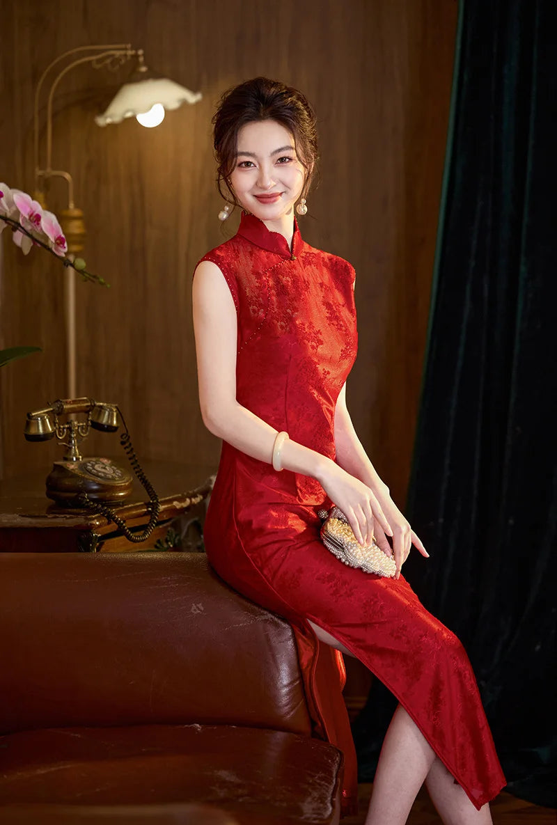 Woman in a Modern Red FLoral Jacquard Sleeveless wedding Qipao Dress  sitting on a leather chair in a room with a vintage phone and lamp.