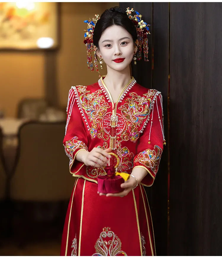 Woman in traditional red embroidered   Modern Red Qun Kwa / Xiuhe Chinese Wedding Gown dress holding a decorative item indoors.