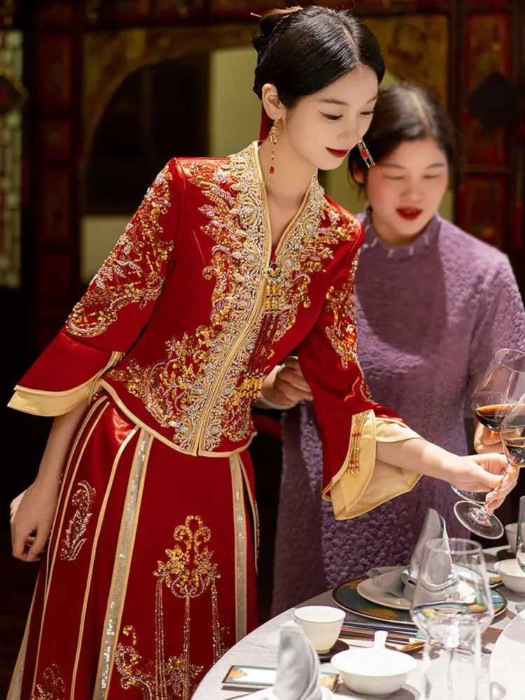 Woman in a red and gold traditional outfit-Modernized V-Neck Chinese Wedding Xiu He Qun Kwa Dress  pouring wine at a table.
