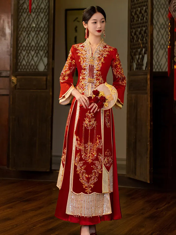 Woman wearing a traditional red and gold embroidered Modernized V-Neck Chinese Wedding Xiu He Qun Kwa  dress in an indoor setting.