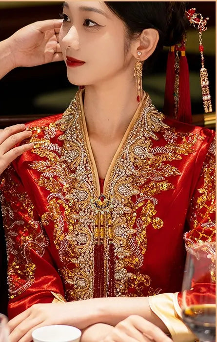 Woman wearing a traditional red and gold Modernized V-Neck Chinese Wedding Xiu He Qun Kwa Dress outfit with intricate designs.