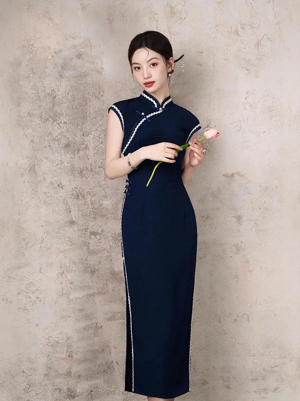 Woman in a Navy Blue Cap Sleeves Jacquard Cotton Qipao Dress holding a pink flower against a beige wall.