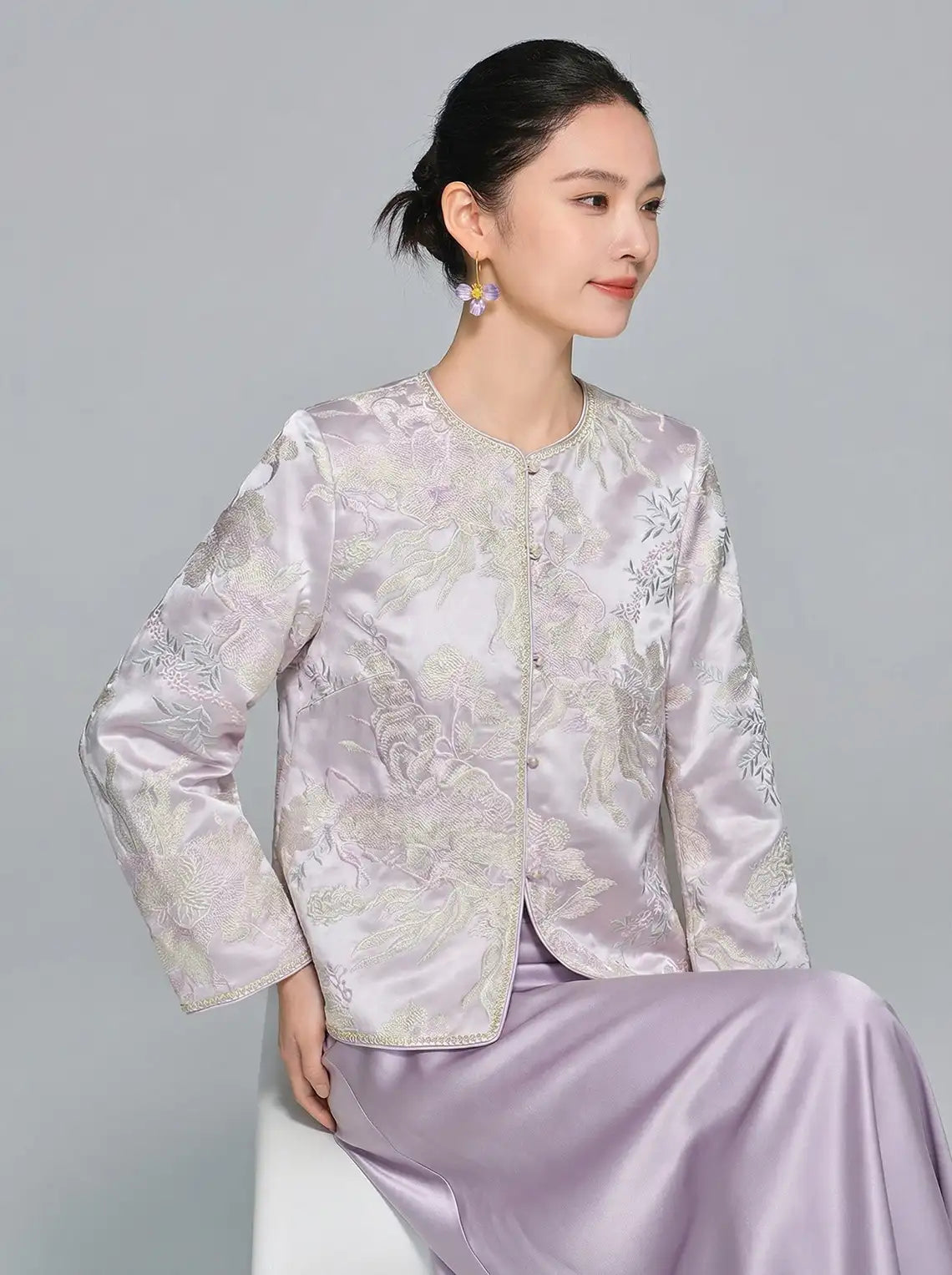 Woman wearing a light purple New Chinese Style Lilac Mist Embroidered Jacket & Satin Midi Skirt  on a gray background