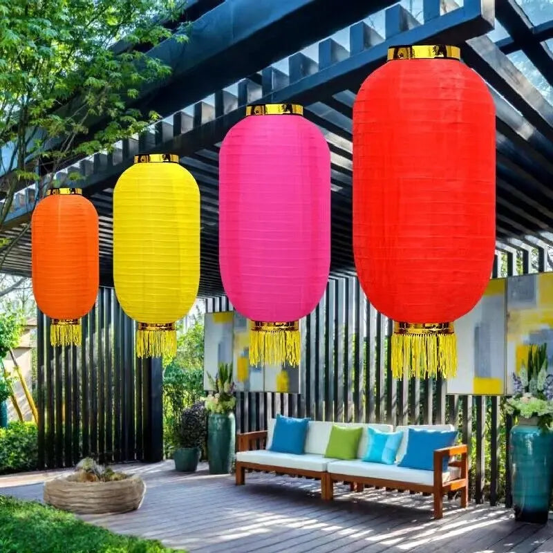 Colorful Nylon Fabric Chinese Lanterns with Tassel  hanging above a wooden bench with colorful cushions in an outdoor setting.