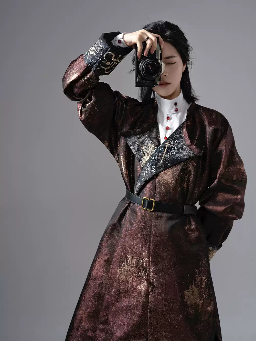 a man in Chinese Reversible Hanfu Robe holding a camera against a gray background