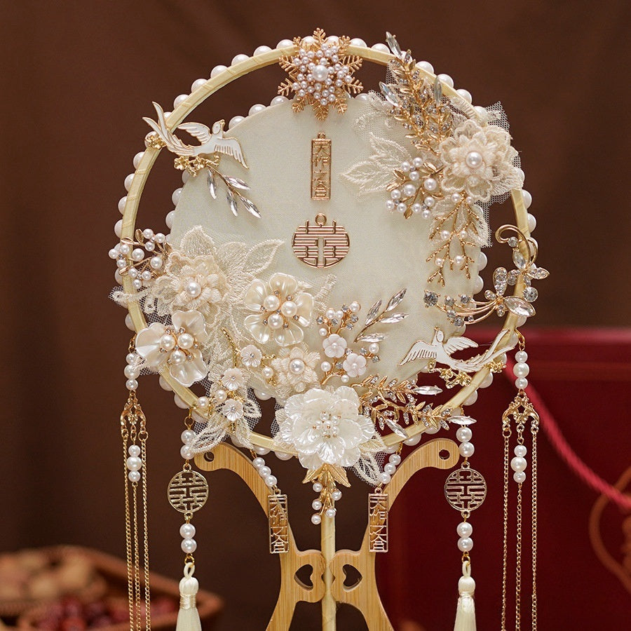 Traditional Ivory White and Golden Chinese Bridal Hand Fan adorned with ornate white lace floral patterns, gold details, delicate pearl accents and ascading tassels