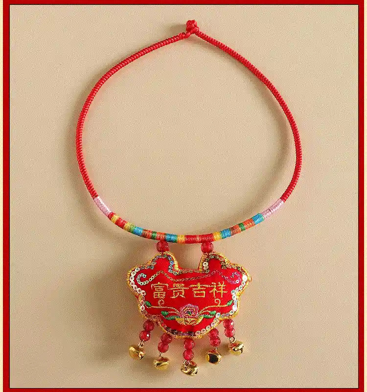 Decorative red string bracelet with a colorful pendant on a beige background