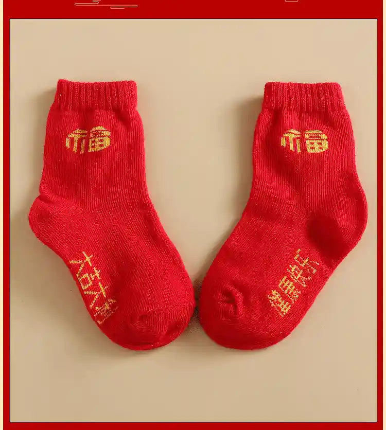 Pair of red socks with gold text on a beige background