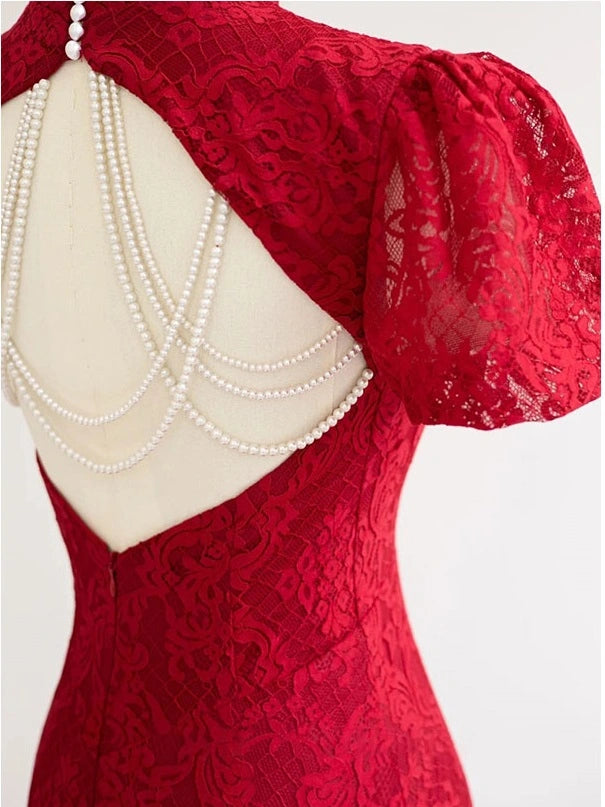 Red lace dress with puff sleeves and a pearl beaded back detail, shown on a mannequin against a light gray background.