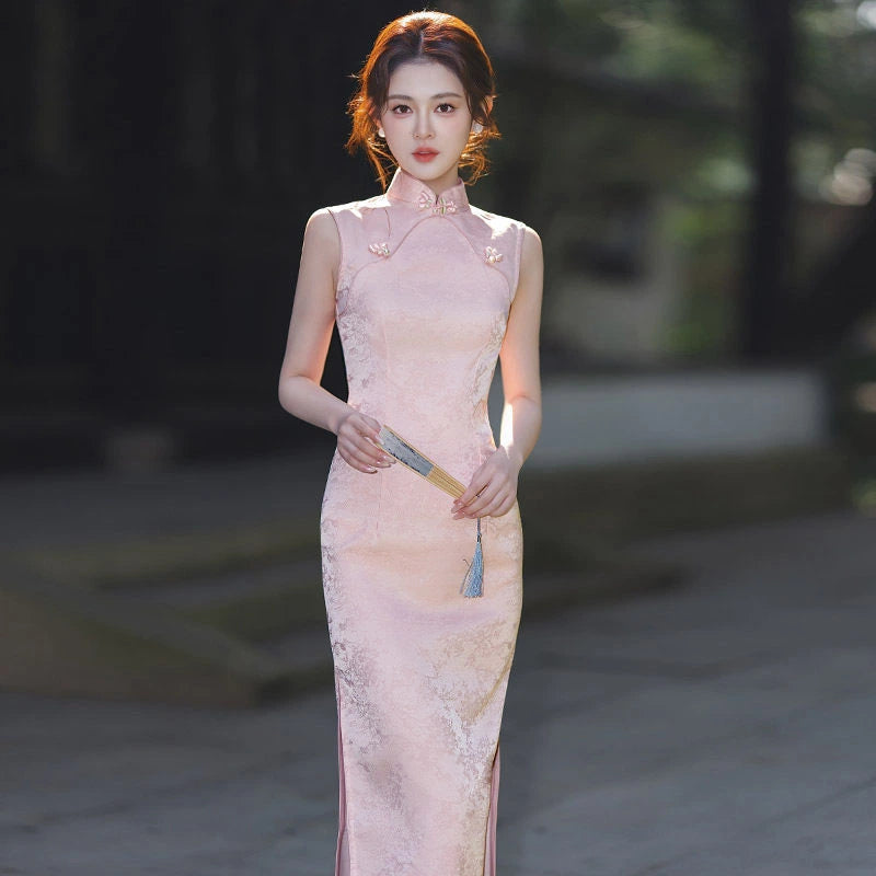 Woman in a traditional Pastel Pink Sleeveless Modern Jacquard Qipao  dress holding a fan in an outdoor setting