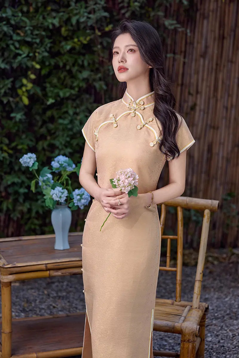 Woman in a Peach traditional  Song Brocade Full-Opening chinese cheongsam  Qipao Dress holding flowers outdoors with greenery and a wooden chair in the background.