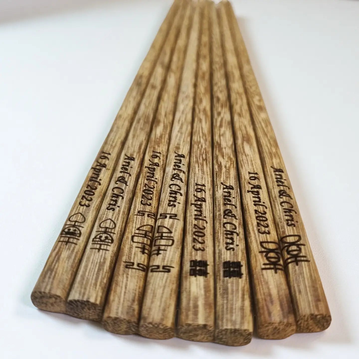 Wooden chopsticks with engraved text on a white background
