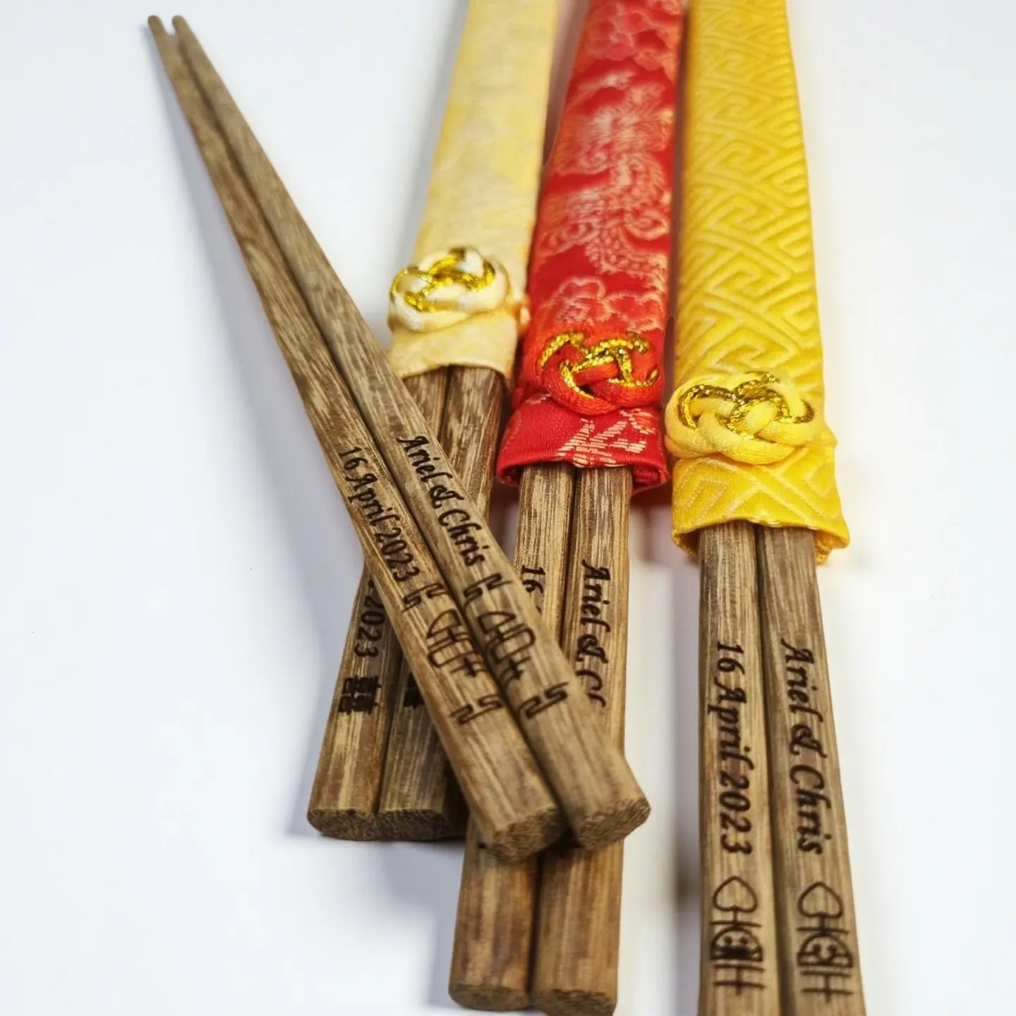 Set of personalized wooden chopsticks with various decorative wraps on a white background