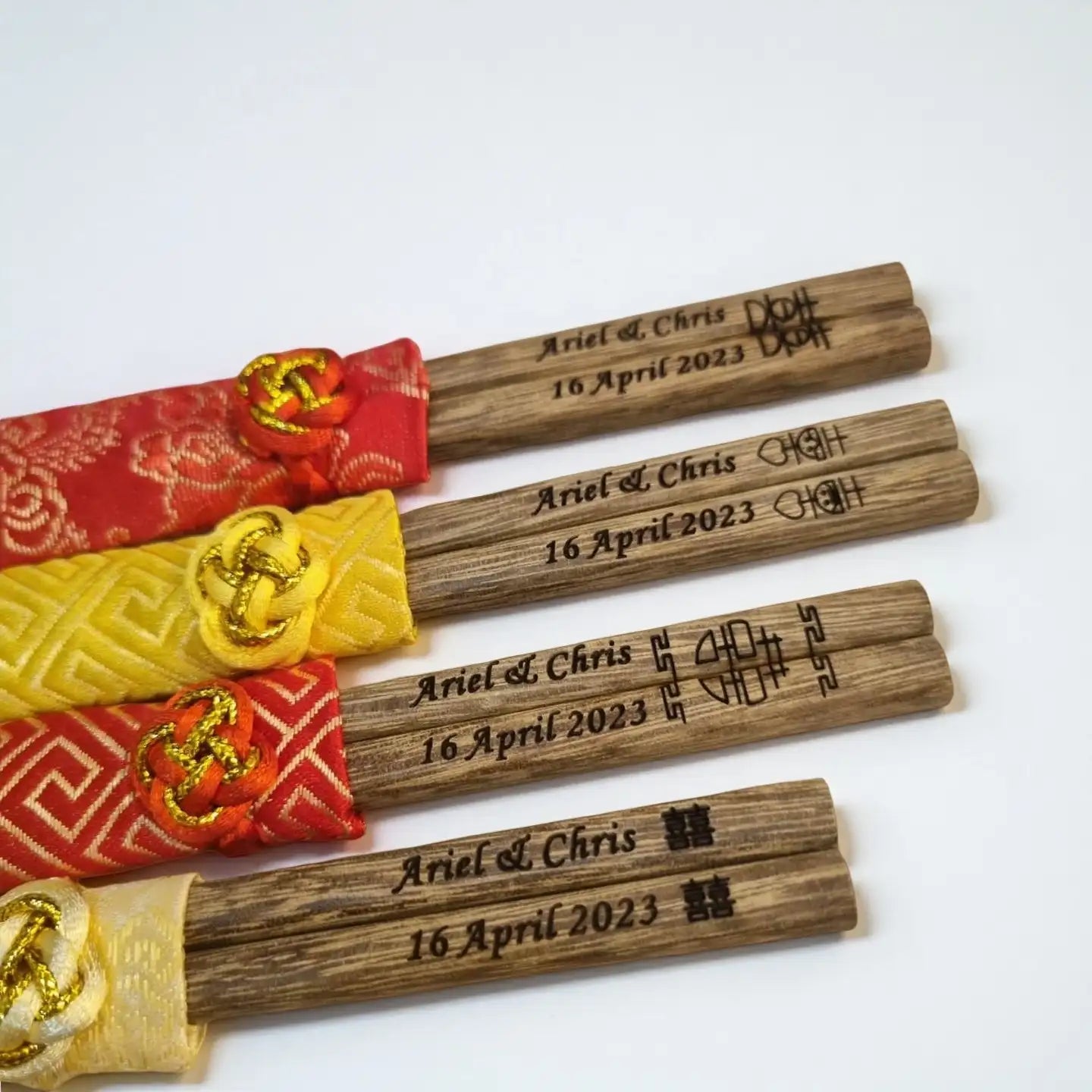 Wooden chopsticks with engraved text and brocade sleeve on a white background