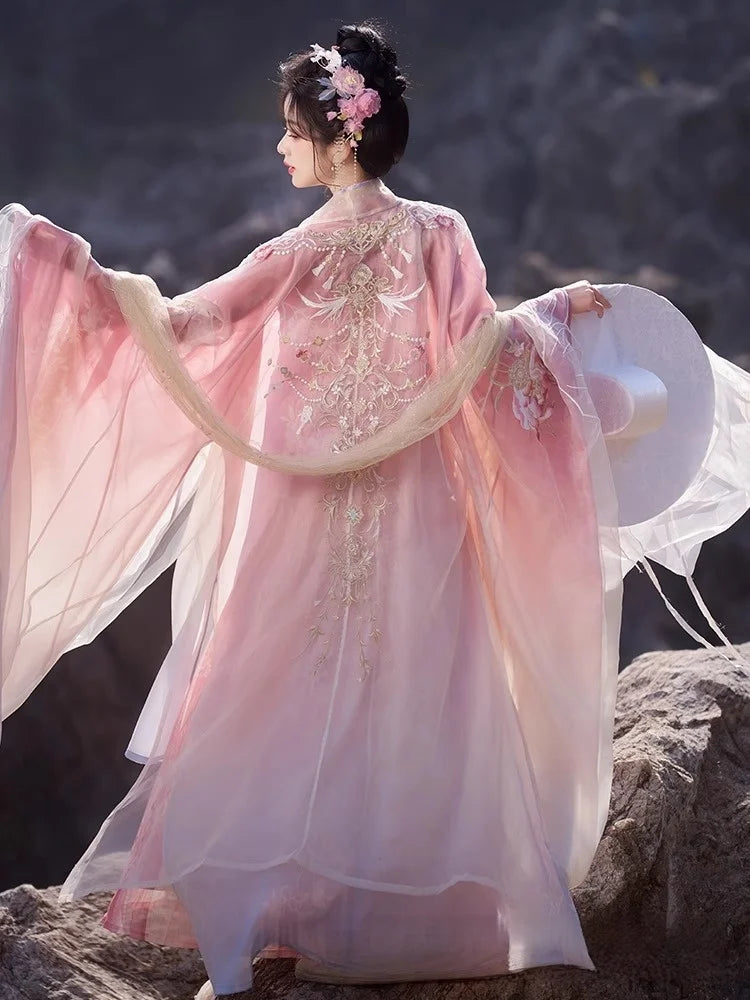 Person in a traditional chinese gown
Pink Embroidered Flowing Tang Dynasty Hanfu Dress standing against a dark, mountainous background.