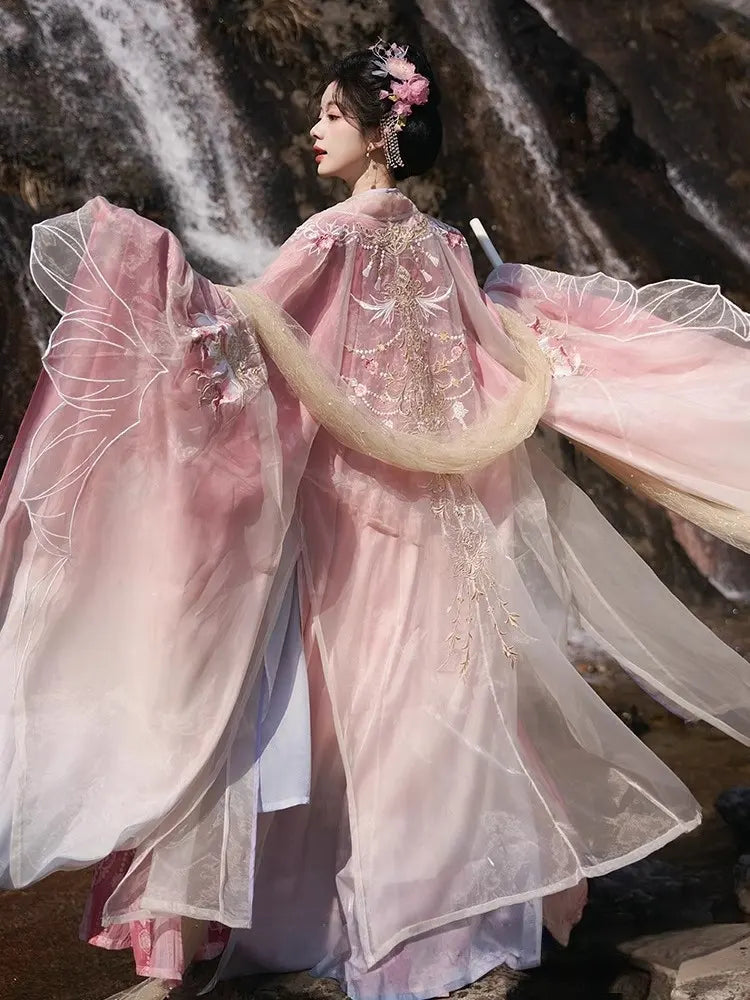Person in a traditional Pink Embroidered Flowing Tang Dynasty Hanfu Dress standing in front of a waterfall