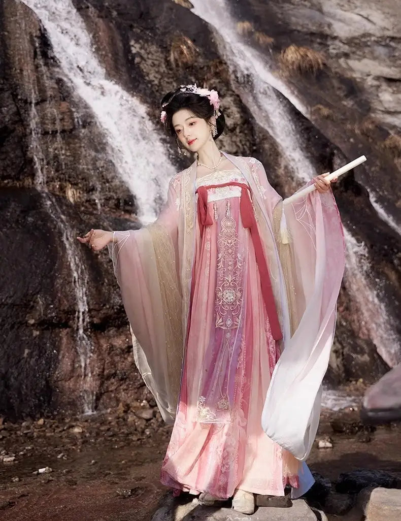 Person in traditional Hanfu attire  Pink Embroidered Flowing Tang Dynasty Hanfu Dress standing in front of a waterfall
