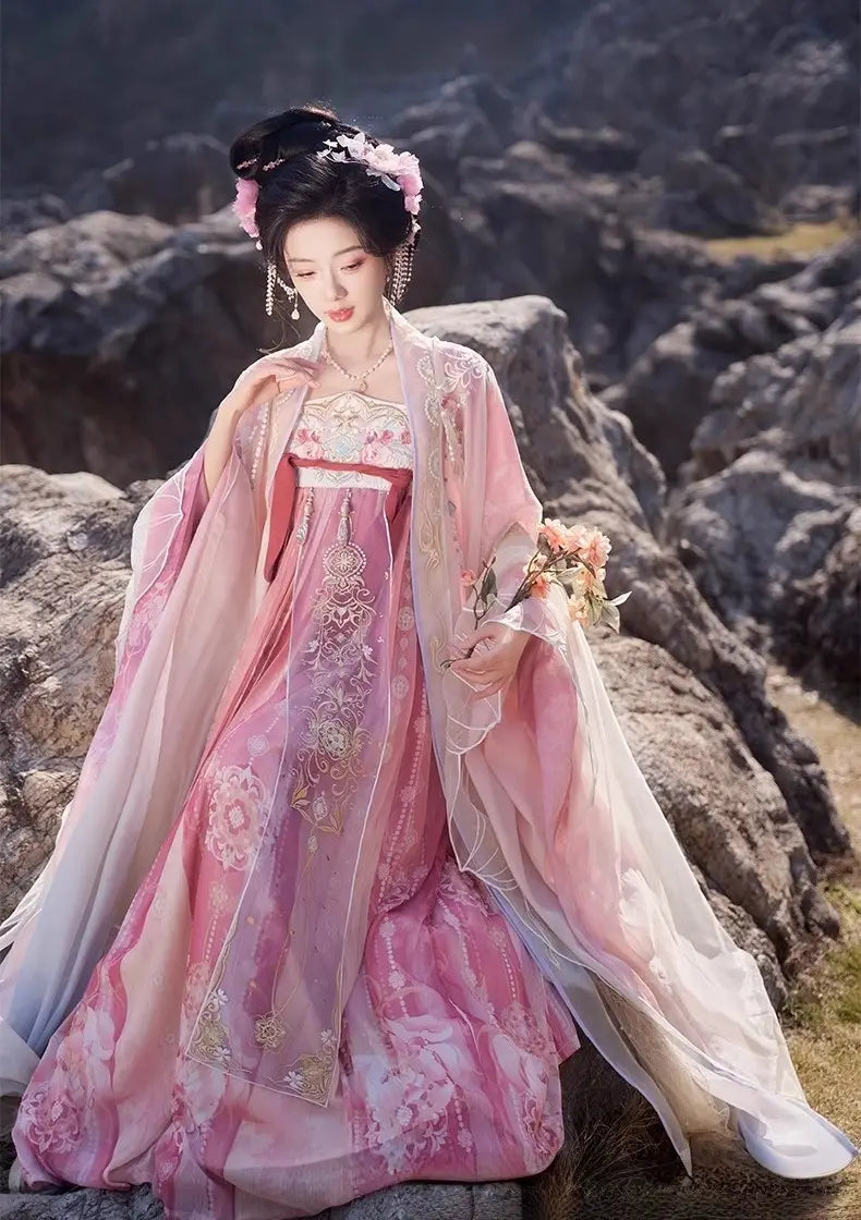 Woman in a traditional Pink Embroidered Flowing Tang Dynasty Hanfu Dress  with floral headpiece standing on rocky terrain