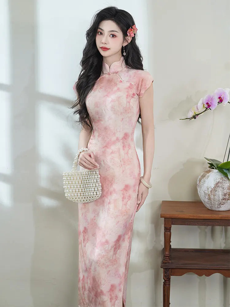 Woman in a Pink Floral Watercolor Long Qipao Dress  holding a beaded handbag indoors.